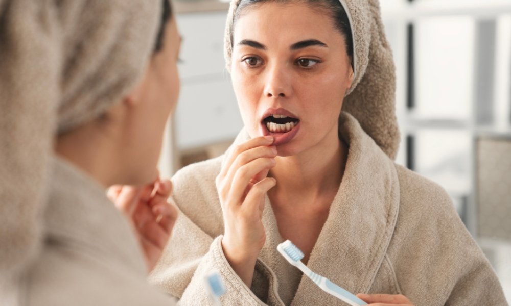 O persoană își verifică dinții în timpul periajului dentar